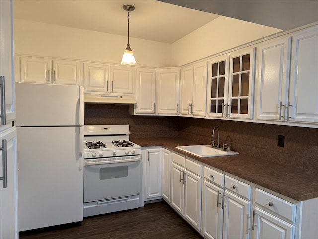 kitchen with under cabinet range hood, white appliances, a sink, white cabinets, and dark countertops