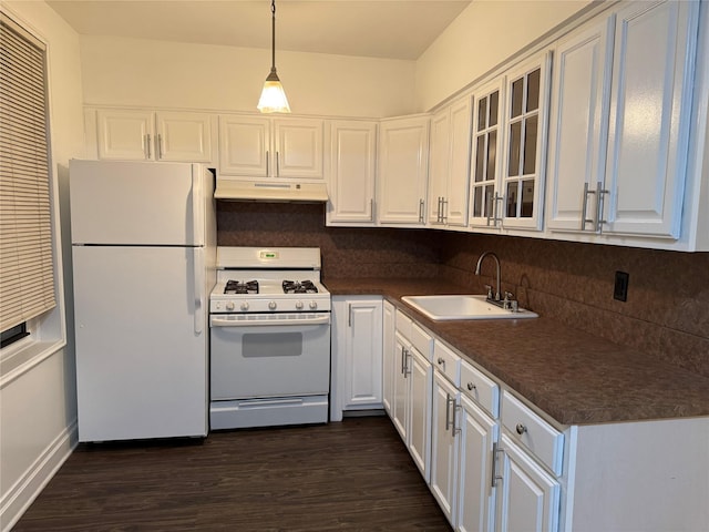 kitchen with dark countertops, white appliances, under cabinet range hood, and a sink