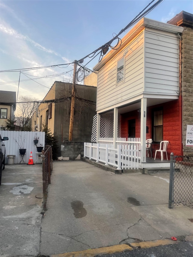 view of home's exterior with a porch and fence