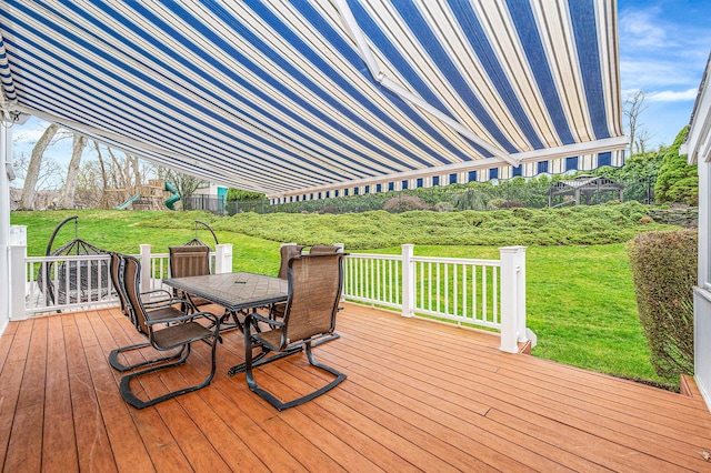 wooden deck featuring outdoor dining space, a playground, and a lawn