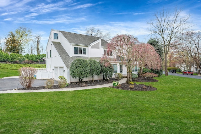 view of side of home with roof with shingles, stucco siding, driveway, an attached garage, and a lawn