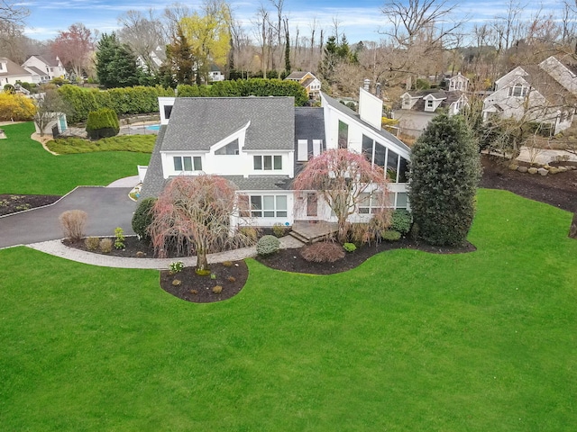 back of house with roof with shingles, a residential view, and a lawn