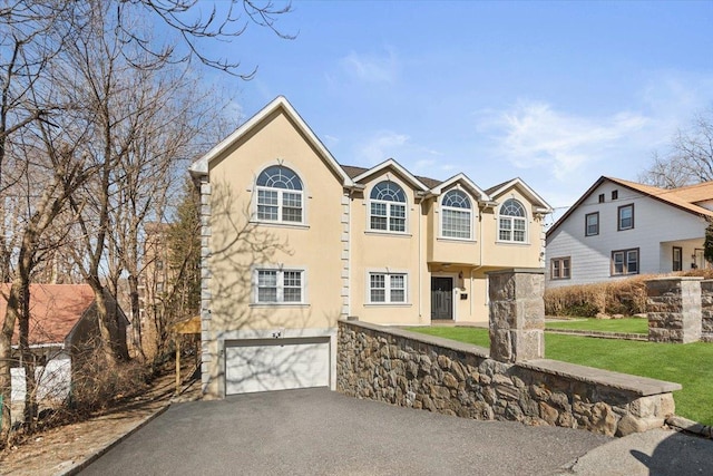 view of front facade with a front lawn, a garage, driveway, and stucco siding