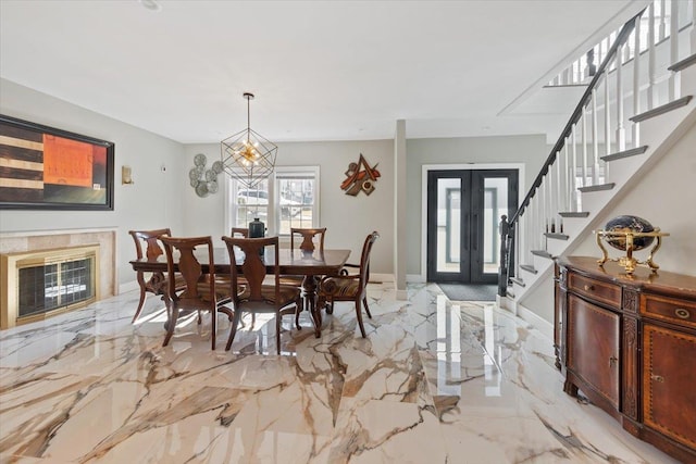 dining space featuring baseboards, stairs, french doors, a notable chandelier, and marble finish floor