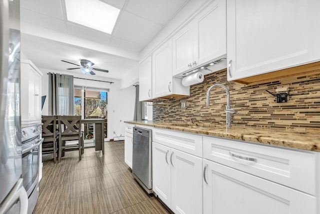 kitchen featuring tasteful backsplash, appliances with stainless steel finishes, white cabinetry, a sink, and ceiling fan