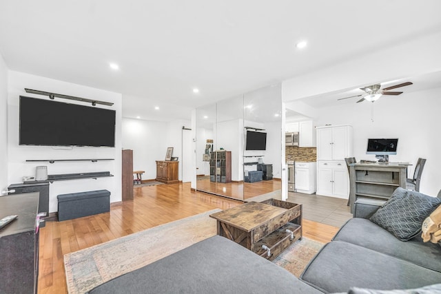 living room featuring light wood-type flooring, a ceiling fan, and recessed lighting