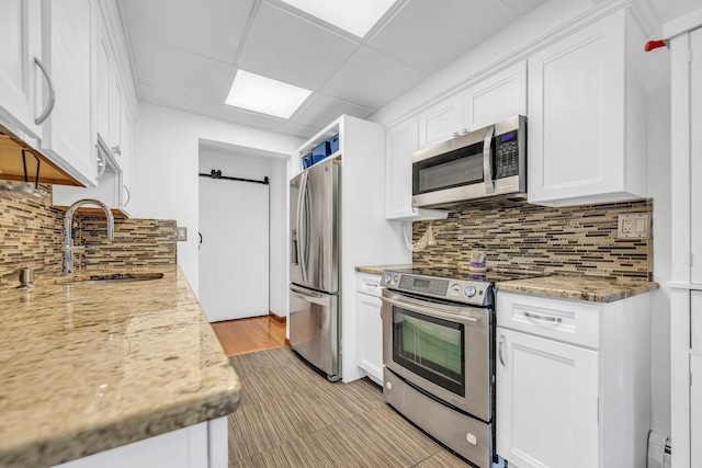 kitchen with stainless steel appliances, a sink, backsplash, and a barn door