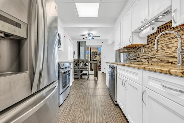 kitchen with white cabinets, a ceiling fan, decorative backsplash, appliances with stainless steel finishes, and a sink