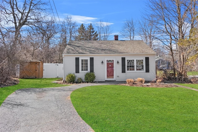 view of front of property with a front lawn, a gate, aphalt driveway, fence, and a chimney