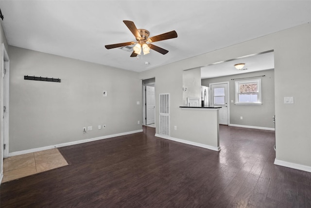 unfurnished living room featuring baseboards, ceiling fan, and dark wood-style flooring