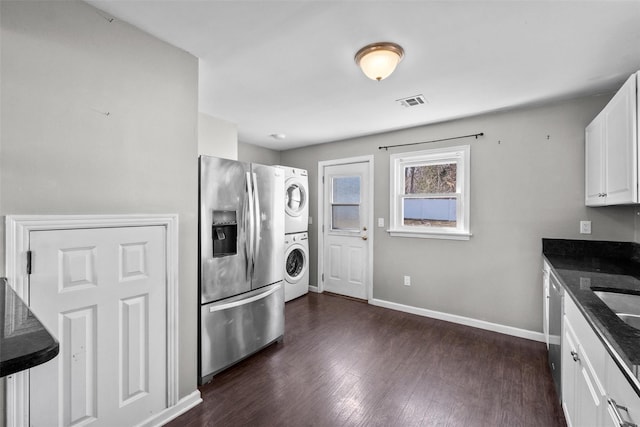 washroom with visible vents, baseboards, laundry area, dark wood-type flooring, and stacked washer / drying machine