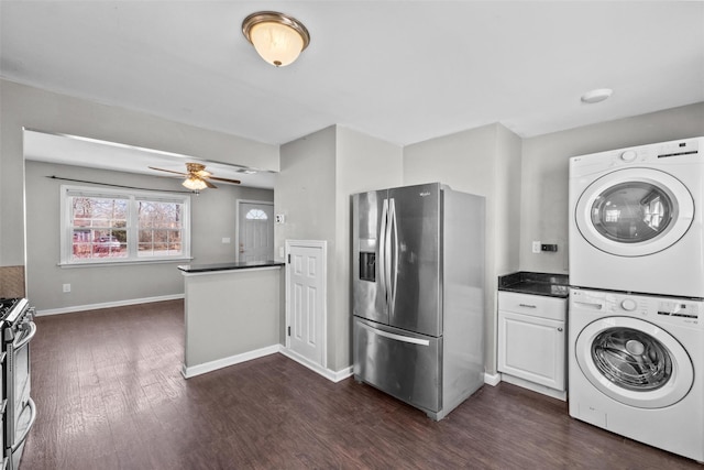 laundry room with baseboards, laundry area, ceiling fan, dark wood-type flooring, and stacked washer and clothes dryer