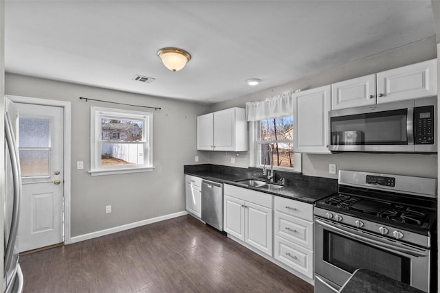 kitchen featuring dark countertops, visible vents, a sink, stainless steel appliances, and dark wood-style flooring