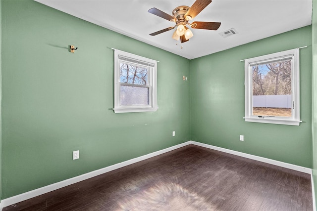 empty room featuring ceiling fan, visible vents, baseboards, and dark wood finished floors