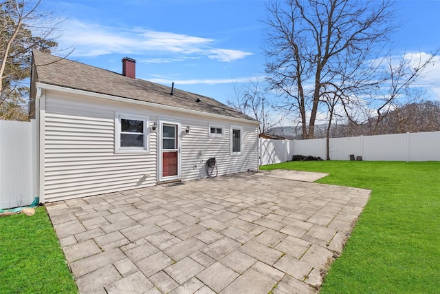 back of house with a patio, a fenced backyard, a shingled roof, a chimney, and a lawn