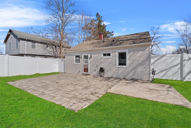 back of house featuring roof with shingles, a yard, a fenced backyard, a chimney, and a patio area