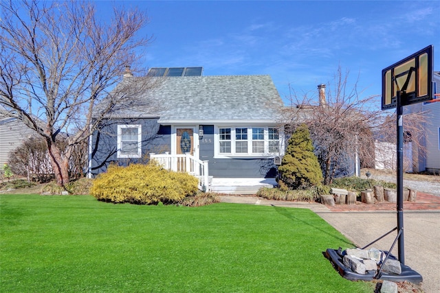 view of front of house with a shingled roof, a front yard, and a chimney