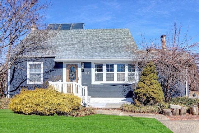 view of front of home with a shingled roof and a front lawn