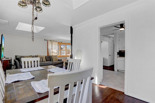 dining area featuring a skylight, crown molding, and wood finished floors