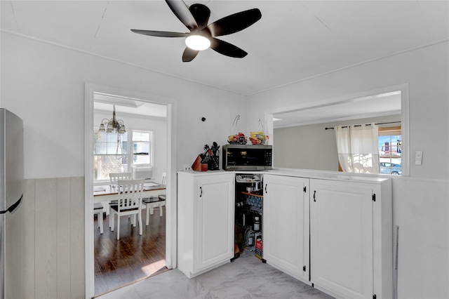 kitchen with marble finish floor, light countertops, appliances with stainless steel finishes, white cabinetry, and ceiling fan with notable chandelier