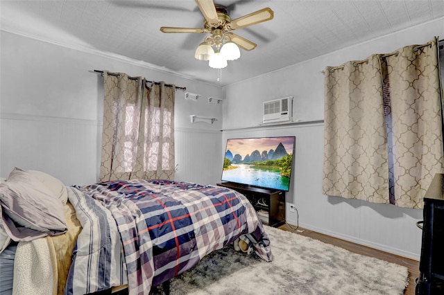 bedroom featuring a wall mounted AC, ceiling fan, wood finished floors, and wainscoting