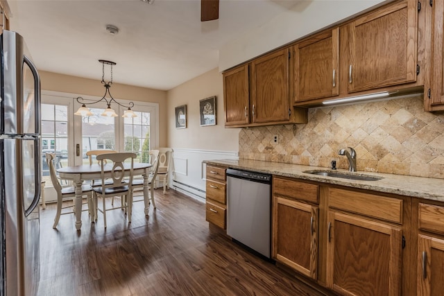 kitchen with stainless steel appliances, tasteful backsplash, brown cabinetry, dark wood-type flooring, and a sink