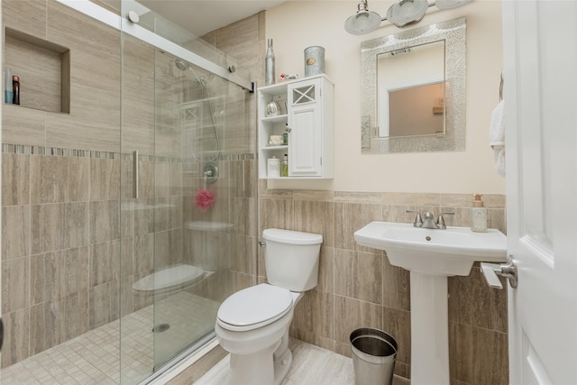 full bathroom with toilet, a wainscoted wall, a shower stall, and tile walls