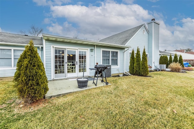 rear view of house featuring a patio, a yard, and a chimney