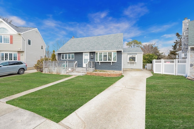 bungalow-style house with a front lawn, a shingled roof, and fence