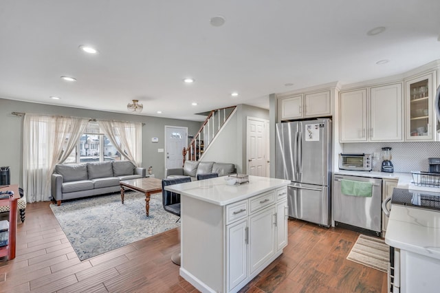 kitchen with open floor plan, stainless steel appliances, dark wood-style flooring, and a toaster