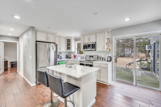 kitchen featuring a kitchen island, appliances with stainless steel finishes, light countertops, and wood finished floors