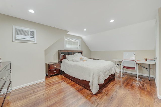 bedroom with lofted ceiling, a wall unit AC, recessed lighting, baseboards, and light wood-style floors