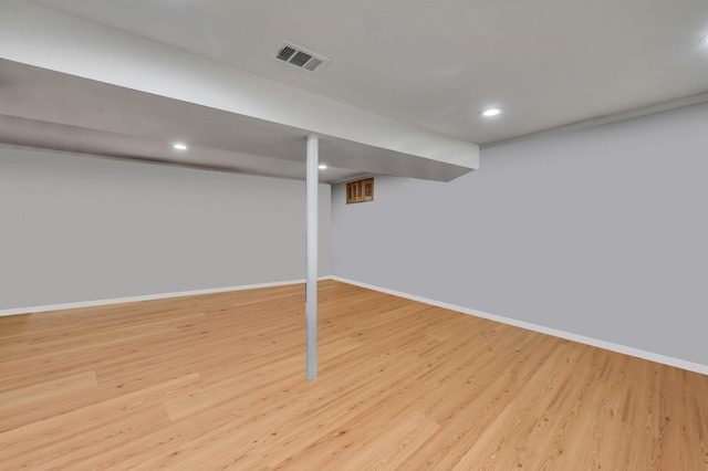 finished basement featuring light wood-style flooring, visible vents, and baseboards