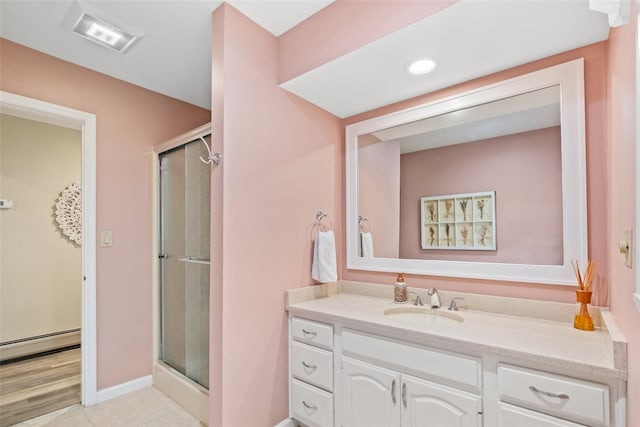 bathroom featuring a baseboard radiator, a shower stall, vanity, and baseboards