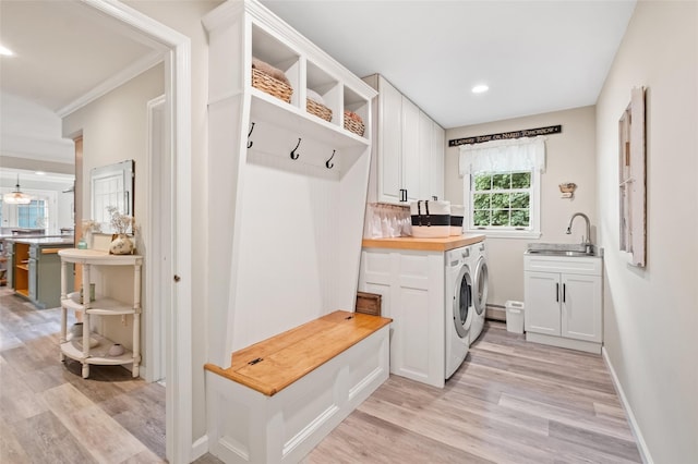 mudroom featuring washing machine and dryer, light wood-style flooring, recessed lighting, a sink, and baseboards