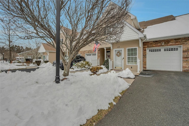 view of front of property with driveway, stone siding, and an attached garage