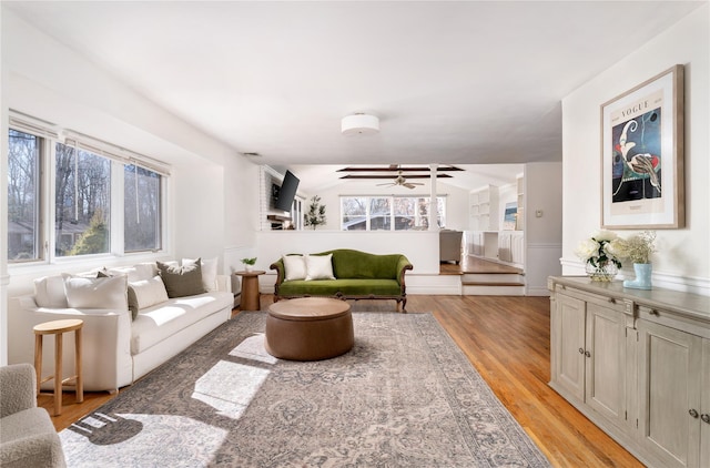 living area with ceiling fan, light wood-style flooring, and vaulted ceiling