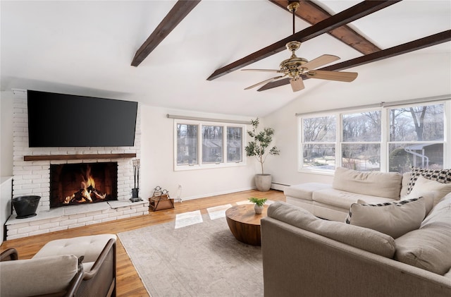 living room featuring lofted ceiling with beams, baseboard heating, a brick fireplace, wood finished floors, and baseboards