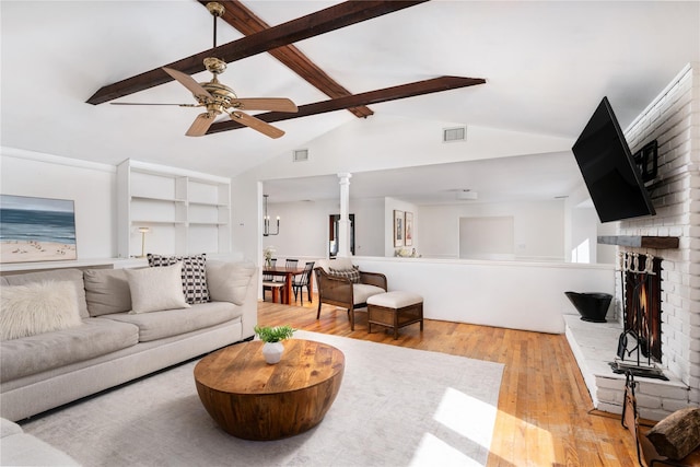 living area with a brick fireplace, visible vents, hardwood / wood-style floors, and beamed ceiling