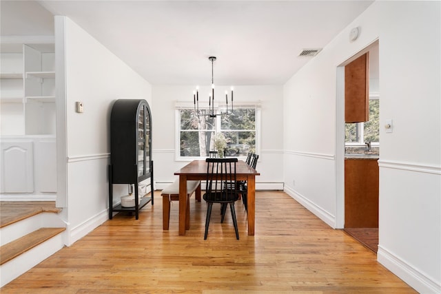 dining area featuring light wood-style flooring, baseboard heating, visible vents, and a chandelier