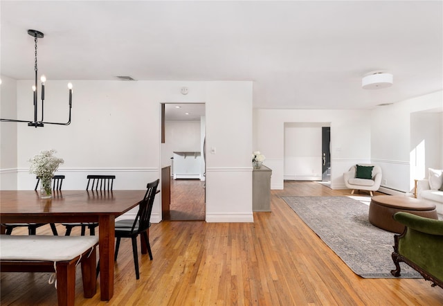 dining area featuring light wood-style flooring, a baseboard radiator, and visible vents