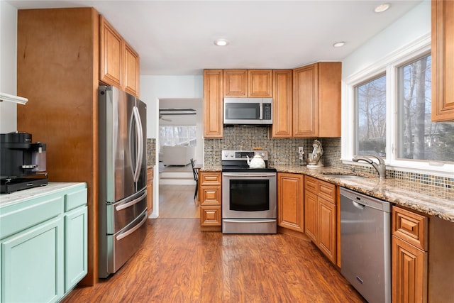 kitchen featuring dark wood-style floors, stainless steel appliances, backsplash, and a sink