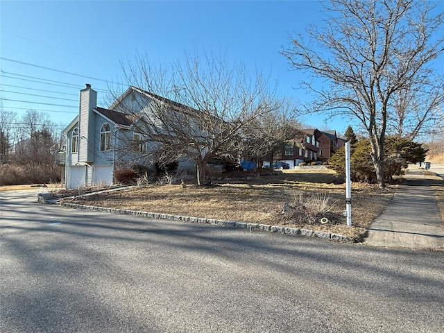 view of front of house with driveway, a chimney, and an attached garage