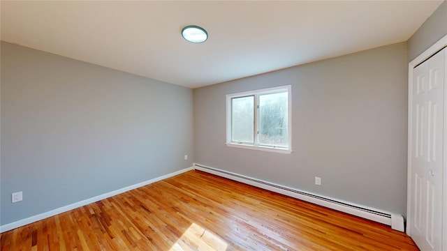 unfurnished bedroom featuring light wood finished floors, baseboards, a baseboard heating unit, and a closet