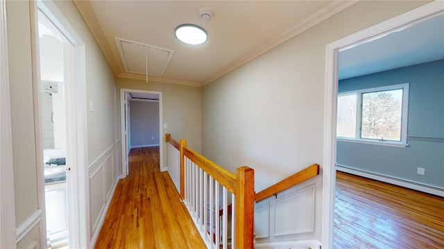 hall with attic access, light wood-type flooring, crown molding, and an upstairs landing