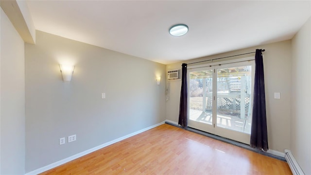 spare room featuring a baseboard heating unit, a wall mounted AC, baseboards, and light wood-style floors