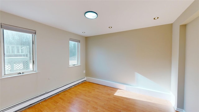 empty room with light wood-style floors, a baseboard radiator, a wealth of natural light, and recessed lighting