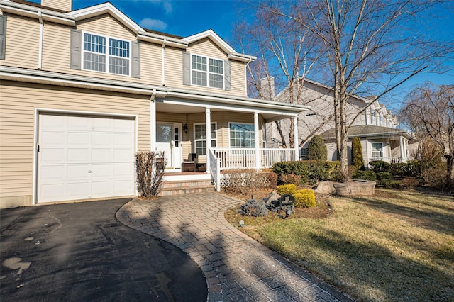 view of front of house with an attached garage, driveway, a porch, and a front yard