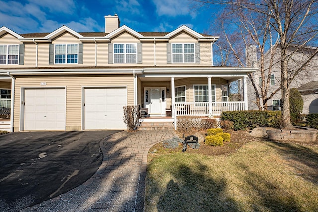 view of front of property featuring driveway, a garage, a chimney, and a porch