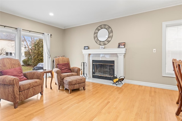 sitting room featuring light wood finished floors, crown molding, and a tile fireplace